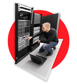 Technician configuring a server rack with a laptop nearby.